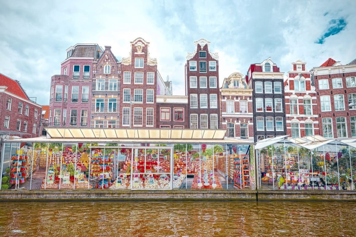 piata de flori din amsterdam, de pe malul unuii canal și clădiri tipic flamande in fundal