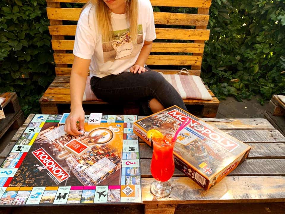 o tânără blondă mută un pion pe planșa unui board game în bucurești, la masa de lemn a unui bar