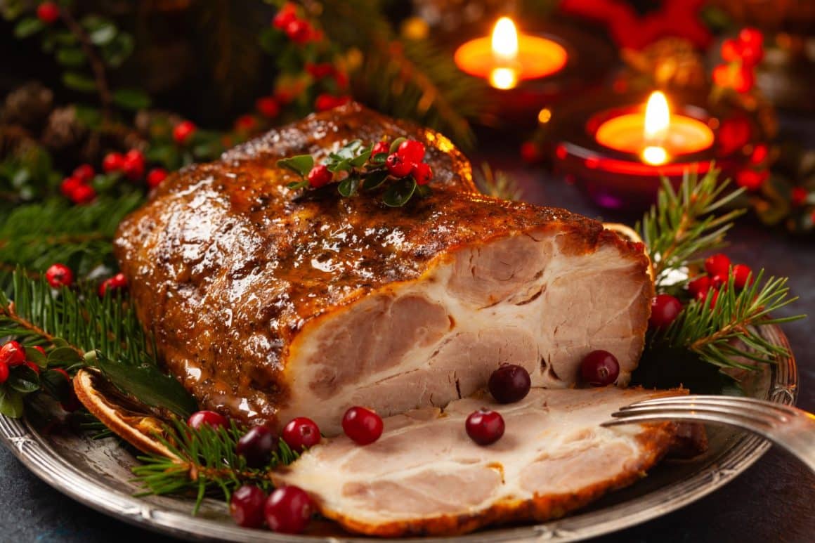 Friptura de Crăciun din carne de porc, fotografiata close up, decorata cu coacaze si crengute de brad