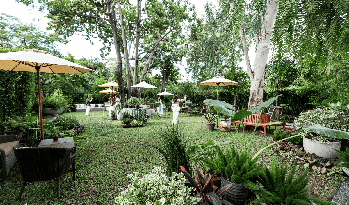 gradina unui restaurant din thailanda, plină de vegetatie și cateva mese de gradina cu umbreluță