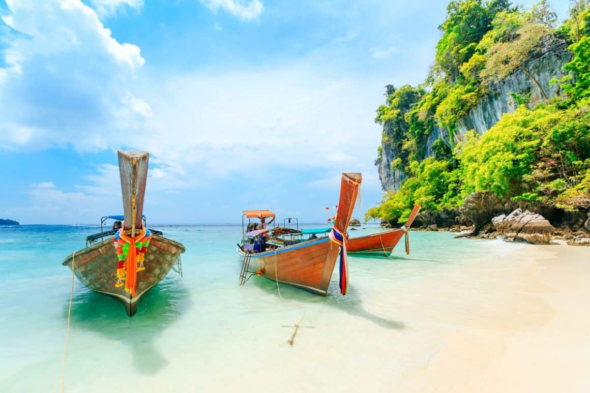 trei ambarcațiuni sunt ancorate la malul mării din thailanda, pe o plajă exotică
