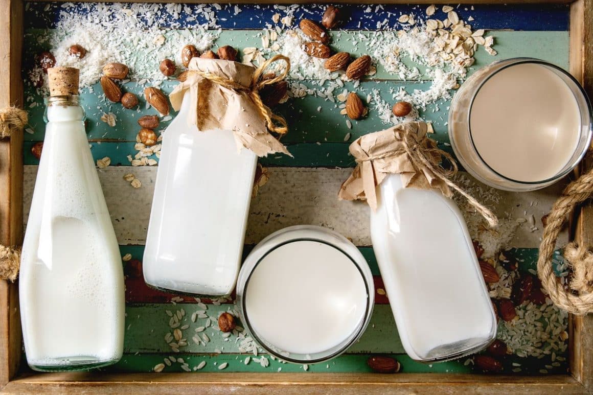 mai multe recipiente cu lactate fermentate sunt asezate pe o tavă de lemn, alături de alte ingrediente naturale