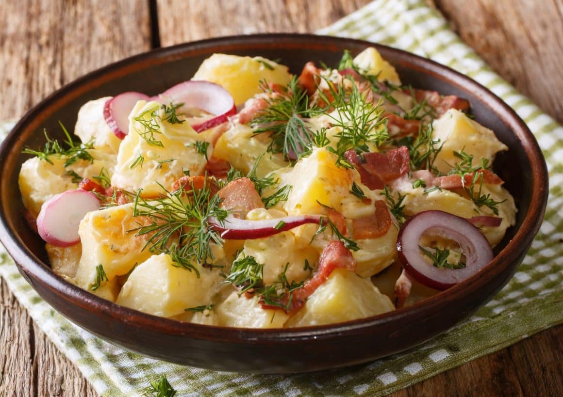 un bol cu mai multe ingrediente folosite la prepararea unei salate calde salate calde, așezat pe un prospo de bucătărie