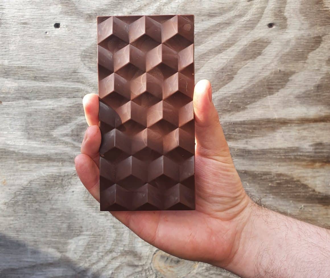 un bărbat ține în mână o tabletă de ciocolată alternativă. una dinre tendințele din domeniul food trends 2024