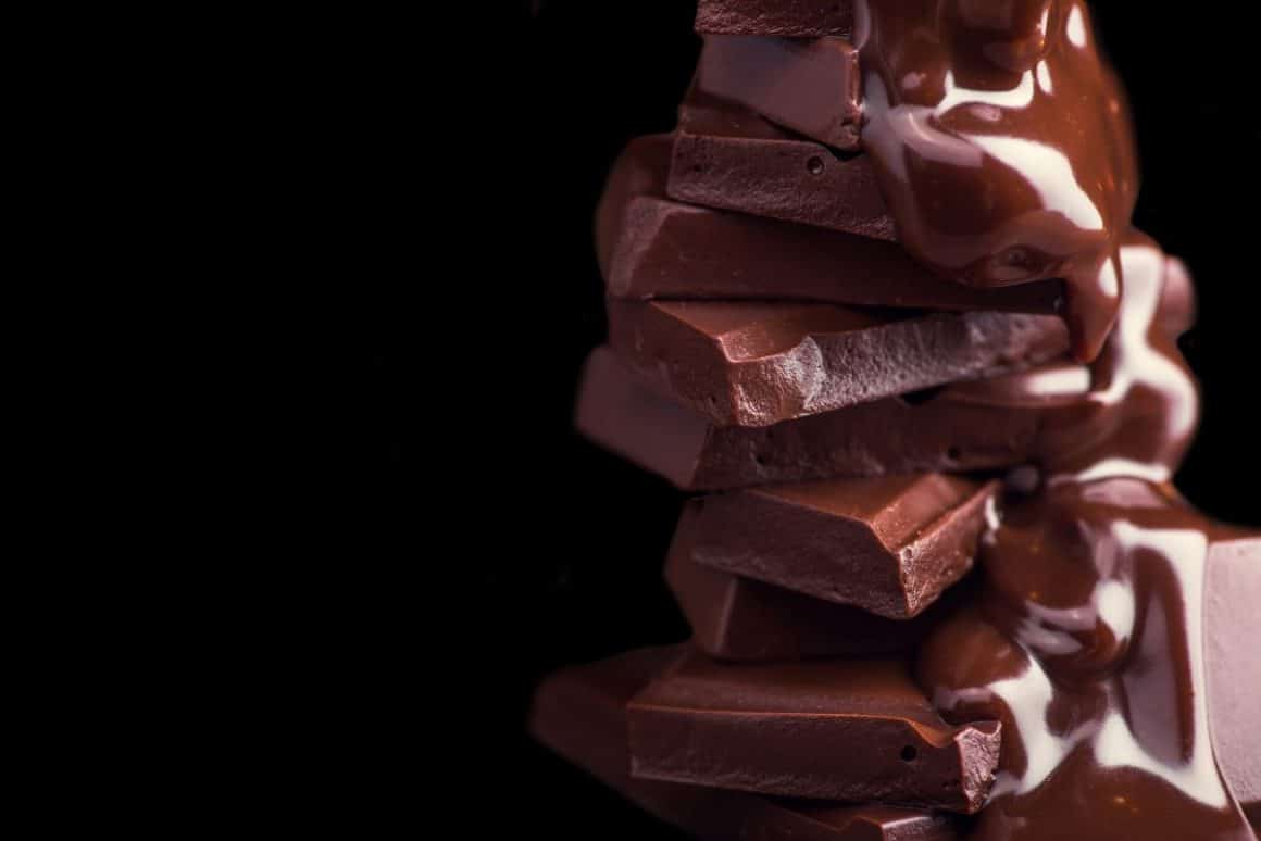 peste mai multe cuburi de ciocolată alternativă se toarnă mai multă ciocolată, topită. una dinre tendințele din domeniul food trends 2024