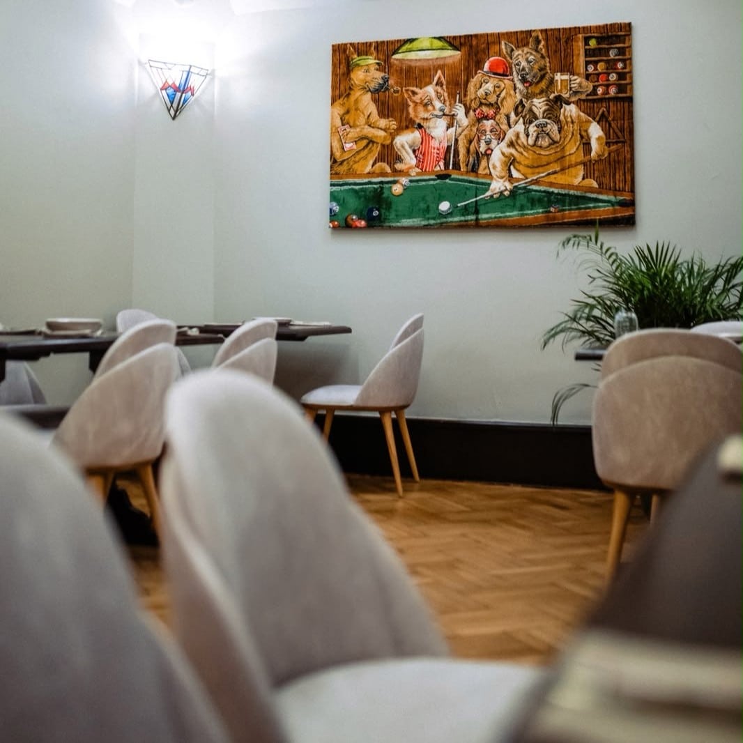 Brera, bistro în București cu decor artistic, scaune tapițate în tonuri neutre și tablouri cu ilustrații originale.