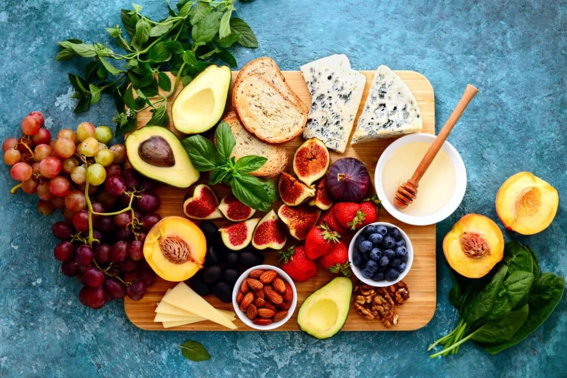 un platou de lemn cu mai multe fructe, felii de pâine și brânză. una dinre tendințele din domeniul food atrends 2024