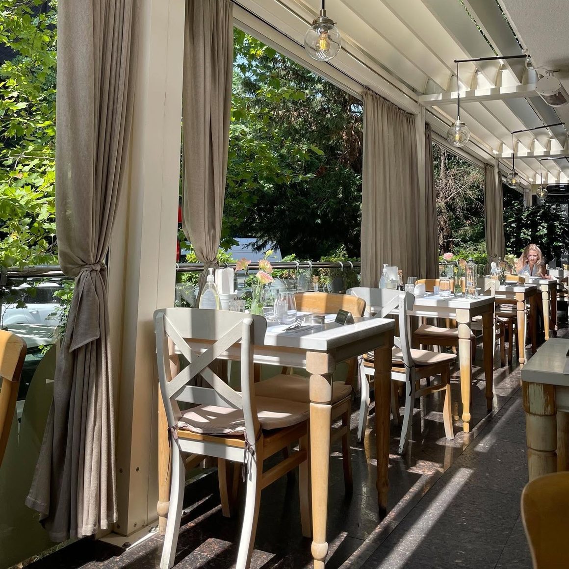 Bistrouri București: terasa luminoasă și elegantă Fior di Latte, cu mese pregătite pentru prânz și cină.