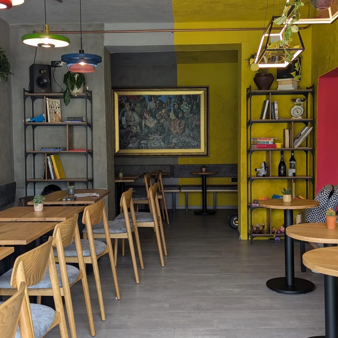 Interiorul Pavlov Gastrobar, amenajat cu pereți galbeni și gri, mobilier din lemn, rafturi decorative și corpuri de iluminat colorate.