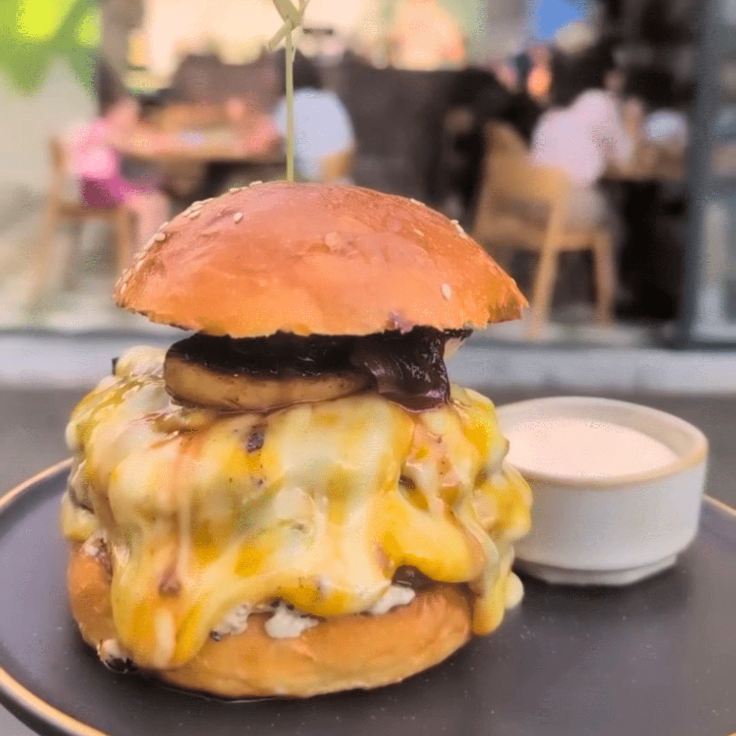 Burger Snob de la Pavlov Gastrobar, cu chiflă pufoasă, carne și brânză topită, servit cu chipsuri de cartofi și sos Calypso.