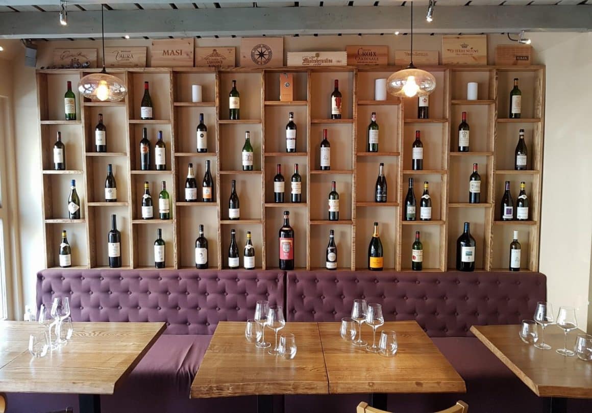 mese si canapea asezate in fata unui perete plin cu rafturi cu vin la Tasting Room by Ethic Wine