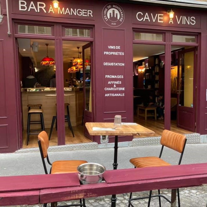 o masa cu 2 scaune in fata restaurantului Vignes du Clos, cu geamuri mari si pereti grena