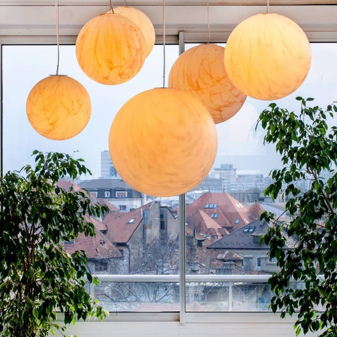 Corp de iluminat sub forma unor sfere glabene, aprinse, iar in fundal priveliste panoramica asupra caselor din Dorobanti. Imagine de la SkyBar Dorobanti.