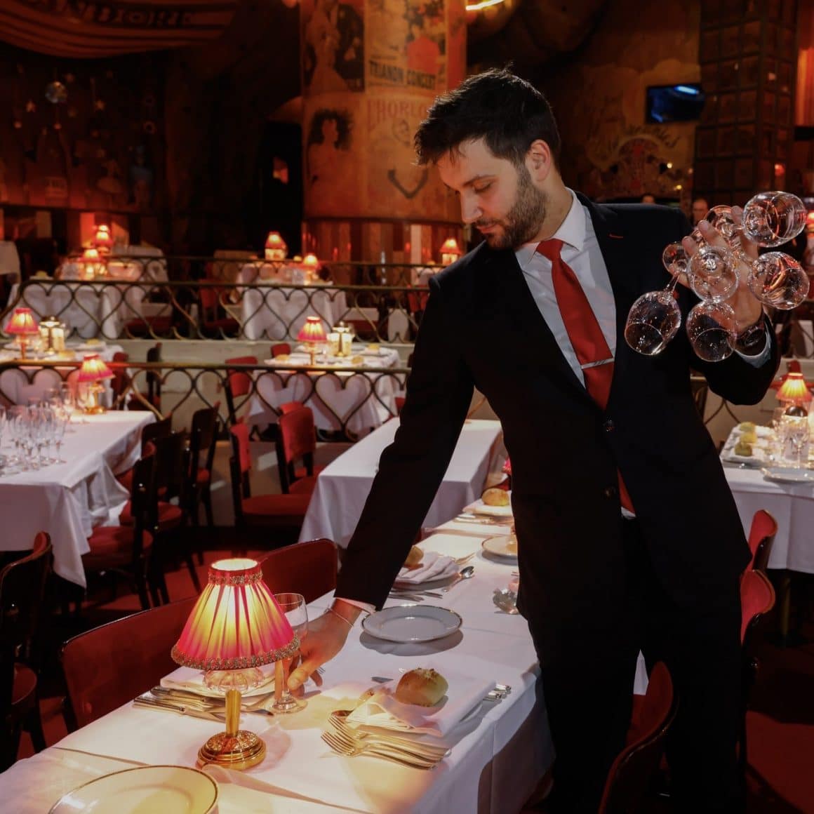 Ospatar elegant aseaza masa pentru o cina la Moulin Rouge, Moulin Rouge
