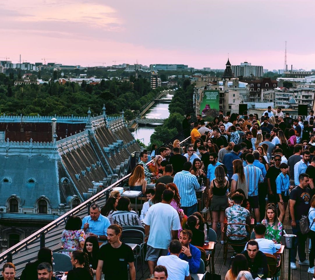 Terasa de la Linea Closer to the Moon, plina de oameni care se distreaza si socializeaza, iar in fundal priveliste panoramica asupra orasului si Cheiul Dambovitei. restaurante la înălțime din București