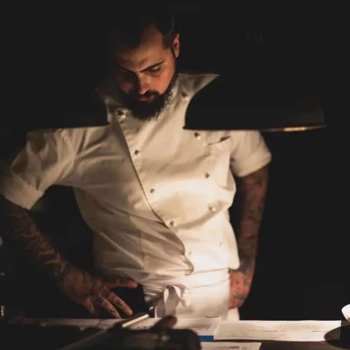 Chef Radu Ionescu de la restaurant Kaiamo, in uniforma de bucatar, fotografiat in semi-intuneric