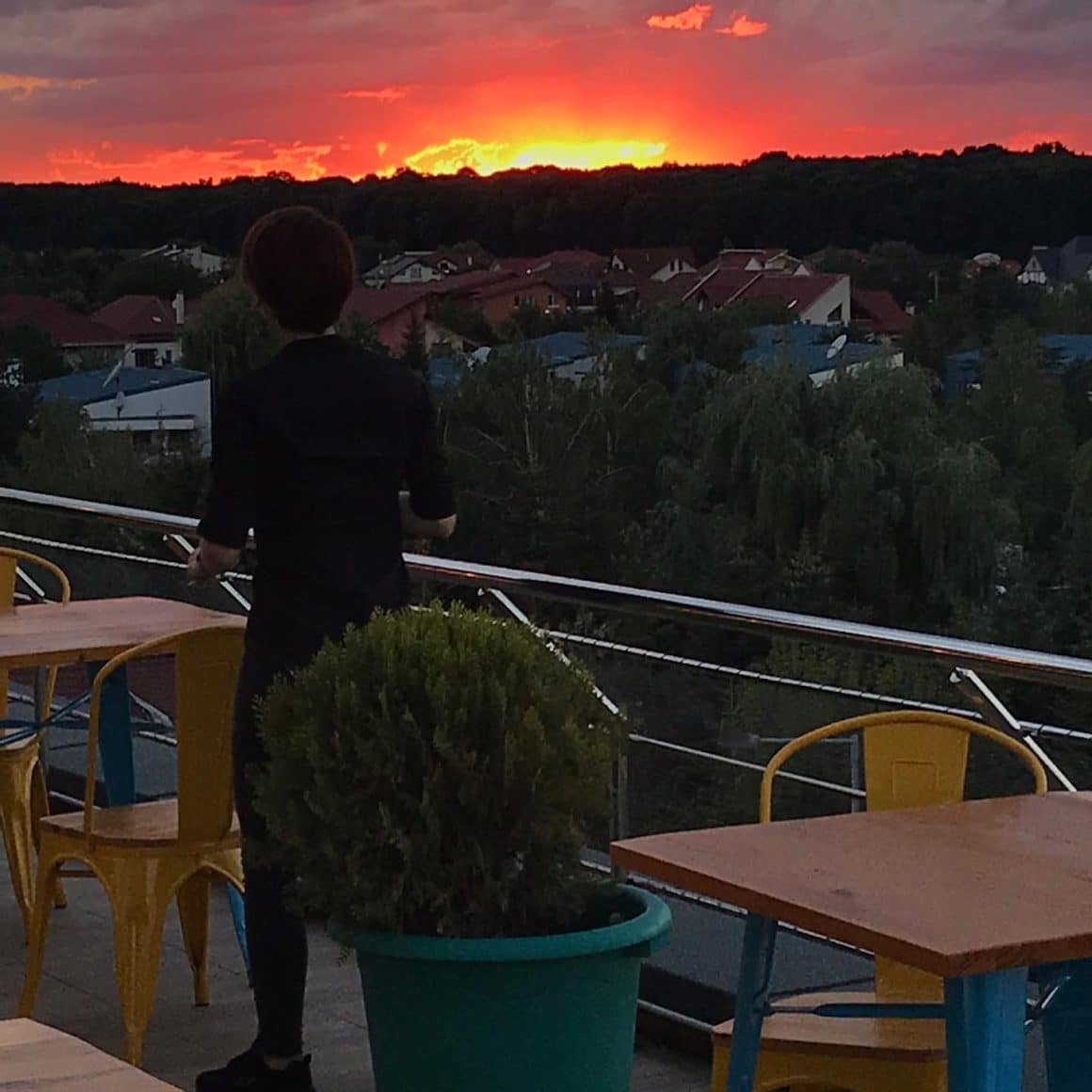 un barbat priveste apusul de pe terasa Elfi Sky Bar, cu priveliste panoramica asupra cartierului Pipera din Bucuresti