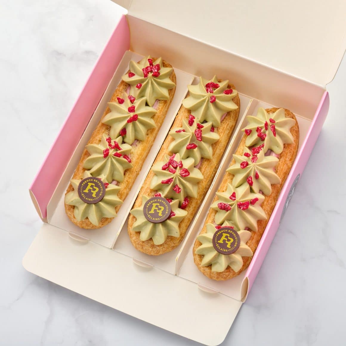Cutie cu 3 eclere Framboise Pistache de la french Revolution de unde poți să-i oferi ceva ceva dulce de Ziua Îndrăgostiților