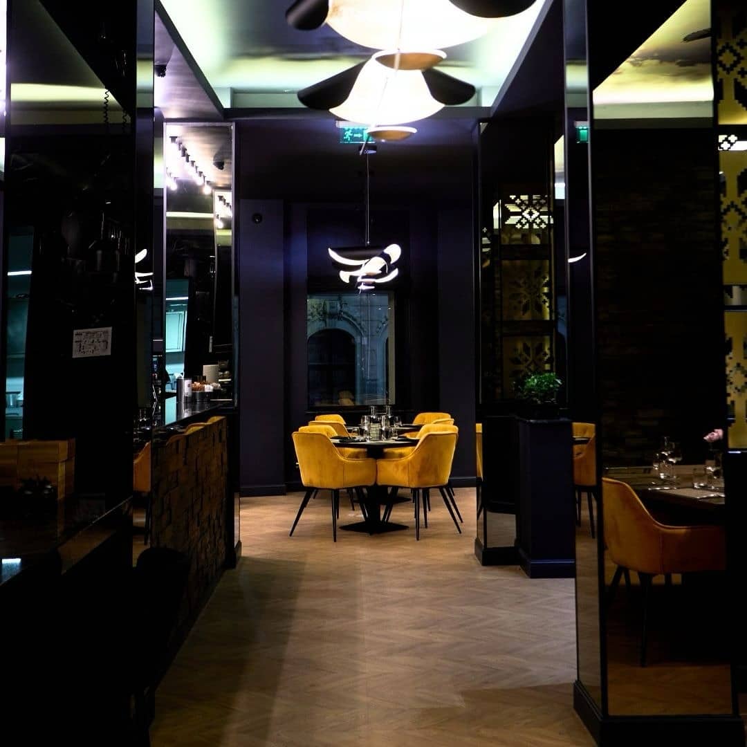 masa cu scaune galbene de catifea, in decorul elegant, intunecat, de la restaurant Boem București
