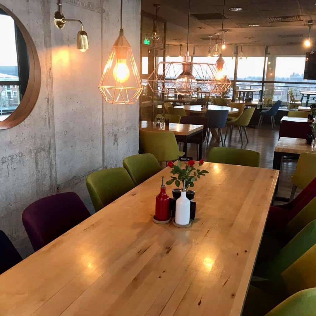 mai multe mese si scaune colorate din interiorul restaurantului Elfi Sky Bar