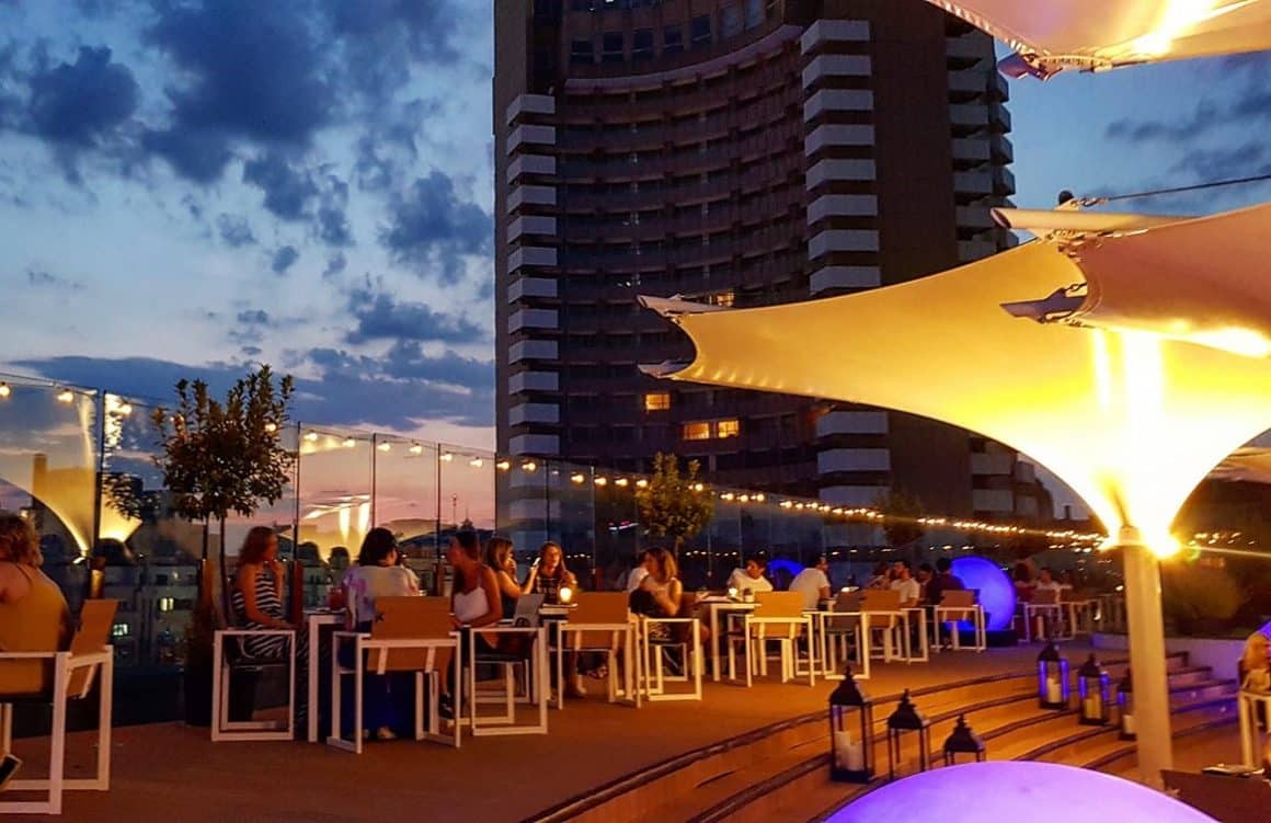 mai multi oameni iau masa pe terasa la Aria Tnb, seara, cu terasa decorata cu luminite decoartive. Unde să mergi la prima întâlnire