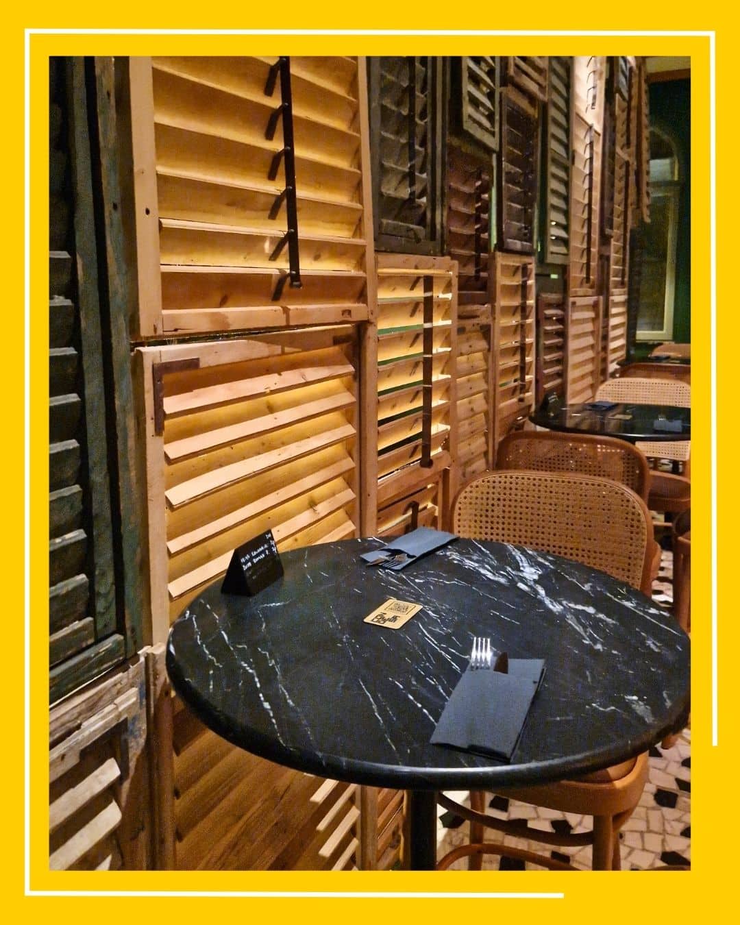 masa rotunda din marmura neagra, in fata unor obloane din lemn, la restaurant Condesa