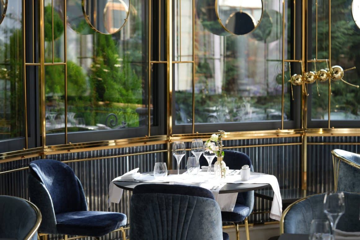Salon din Restaurantul L'Atelier Relais and Chateaux, unul dintre restaurante romantice din București, cu geamuri mari cu storuri, corpuri de iluminat metalice si mobilier clasic, elegant.