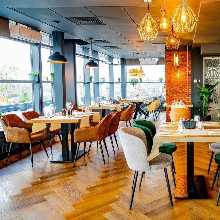 Zona de dining The Urban Nest – restaurante la înălțime – mese din lemn, scaune confortabile și lumină caldă, pentru cine care se prelungesc.