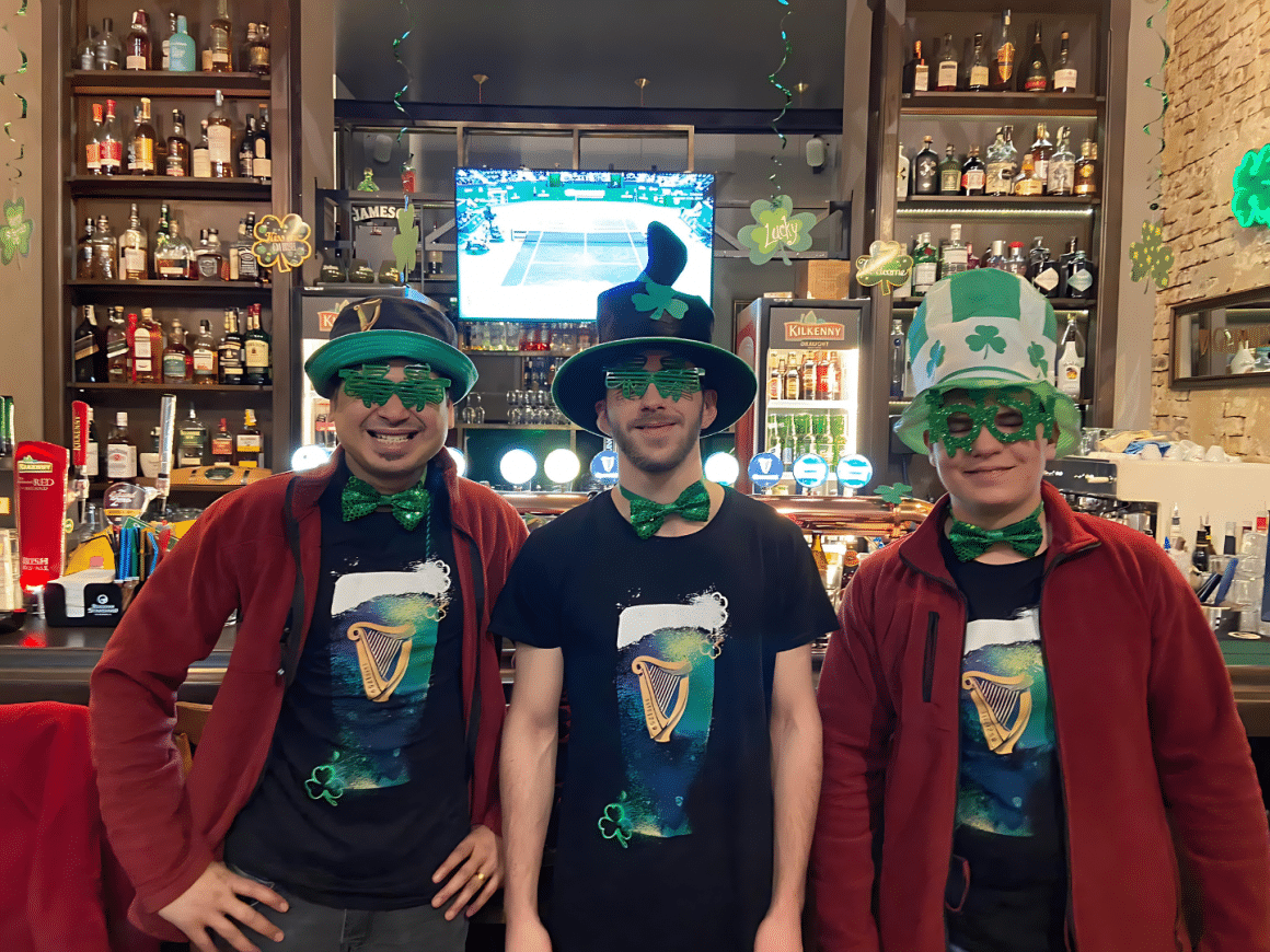 3 barbati costumati cu ochelari papioane si palarii verzi, de st. Patriks Day. Articol despre puburi irlandeze din București si mâncare irlandeza