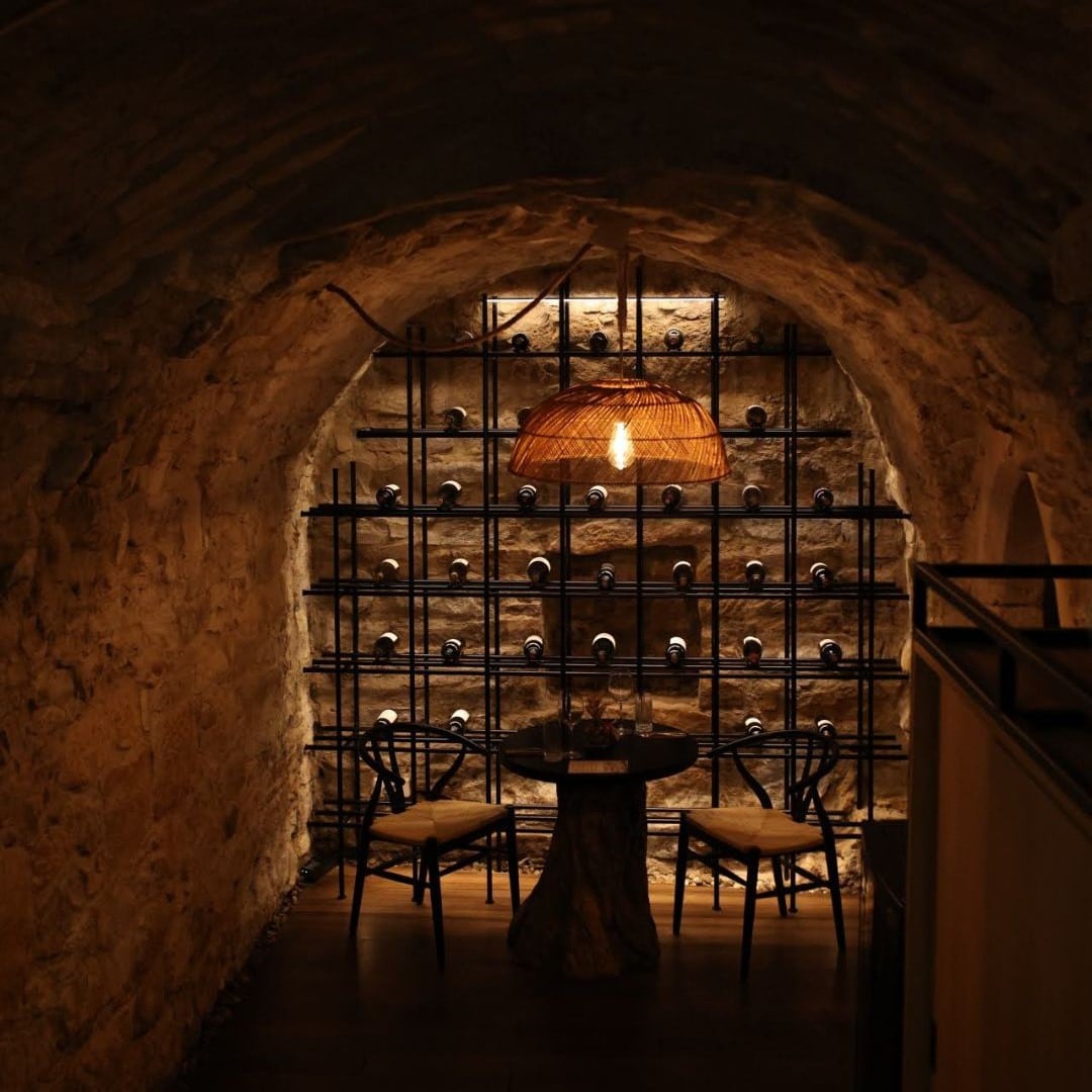 masa de 2 persoane, amplasata in dreptul unui raft cu sticle de vin, intro crama de la restaurant nativ