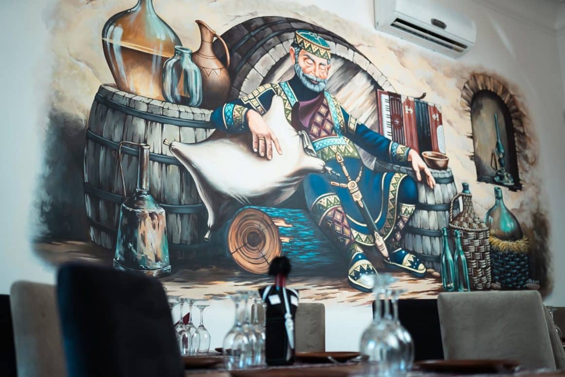 perete cu pictura murala reprezentand un rege adormit intre butoaie de vin de la restaurant Taverna Georgia. Restaurante etnice cu specific deosebit. restaurant georgian.