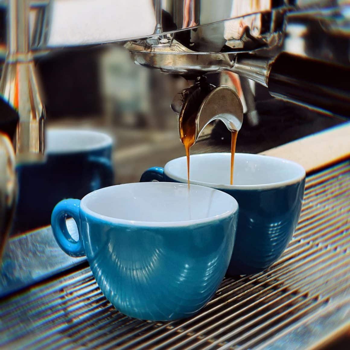 2 cesti albastre in care curgea cafea de la espressor