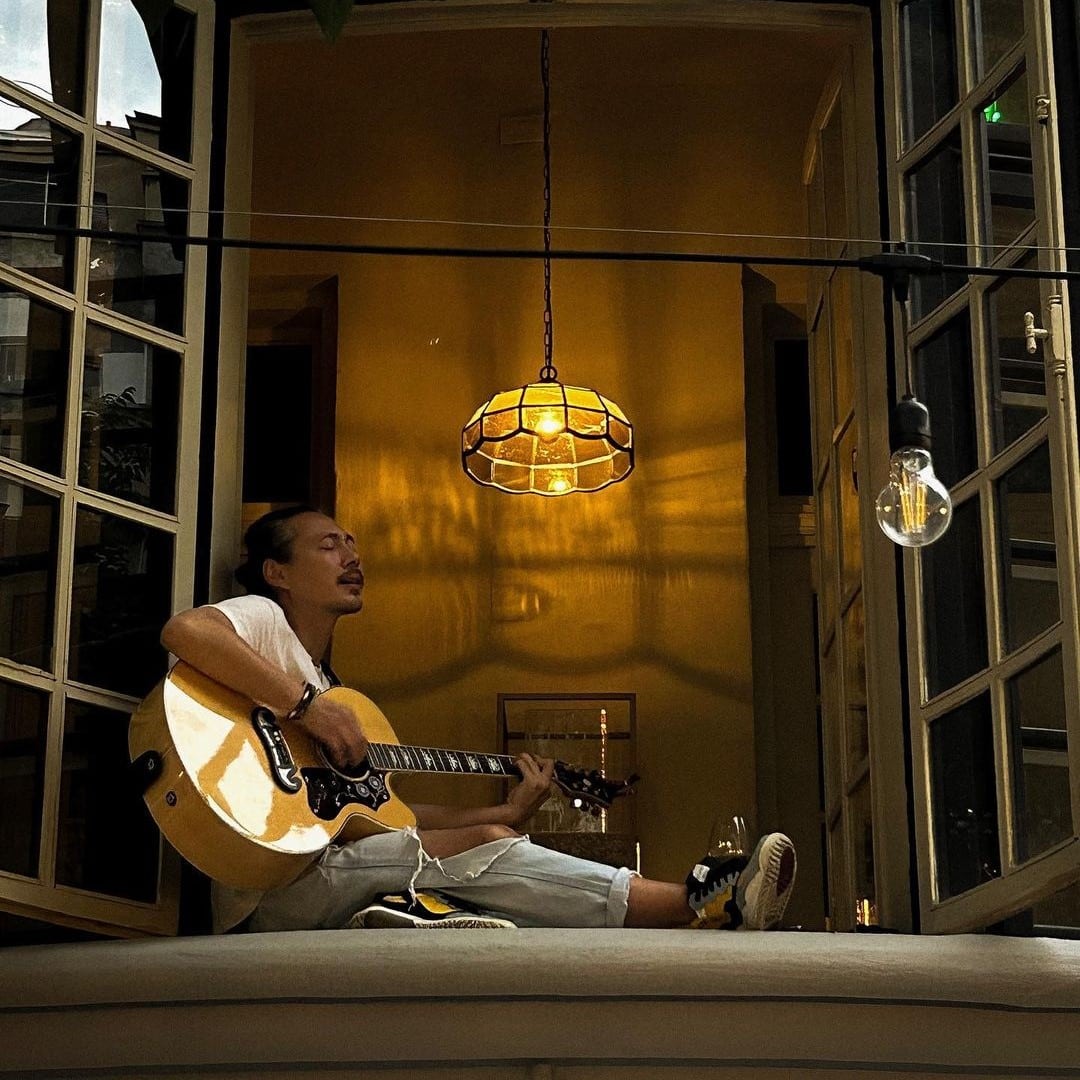 un cantarest la chitara sta asezat pe marginea unei ferestre si canta o serenada