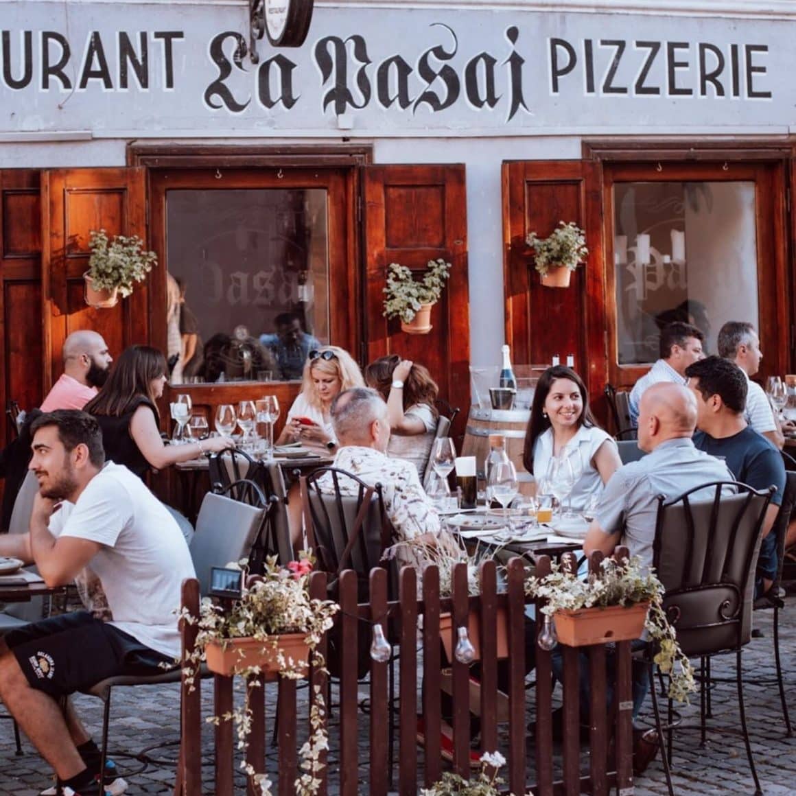 oameni iau masa pe terasa la restaurant pasaj Sibiu