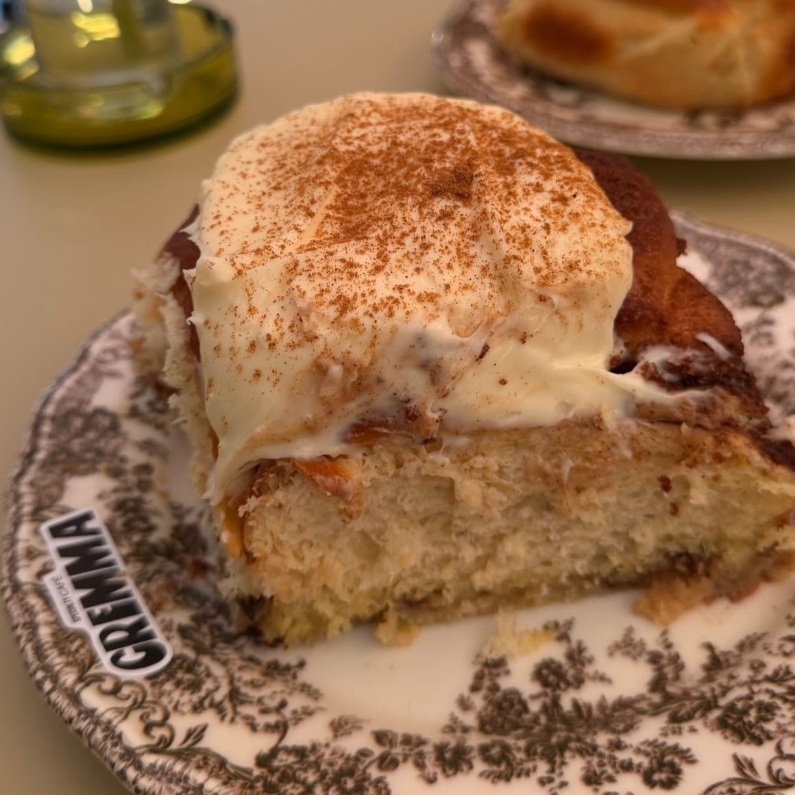 Cinnamon roll pufos cu topping generos de cremă și scorțișoară, la Cremma, în București.