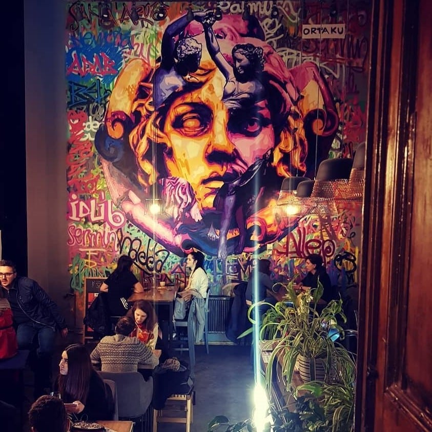 interiorul cafenelei Forma, cu un perete mural pictat cu capul unei statuete si graffiti