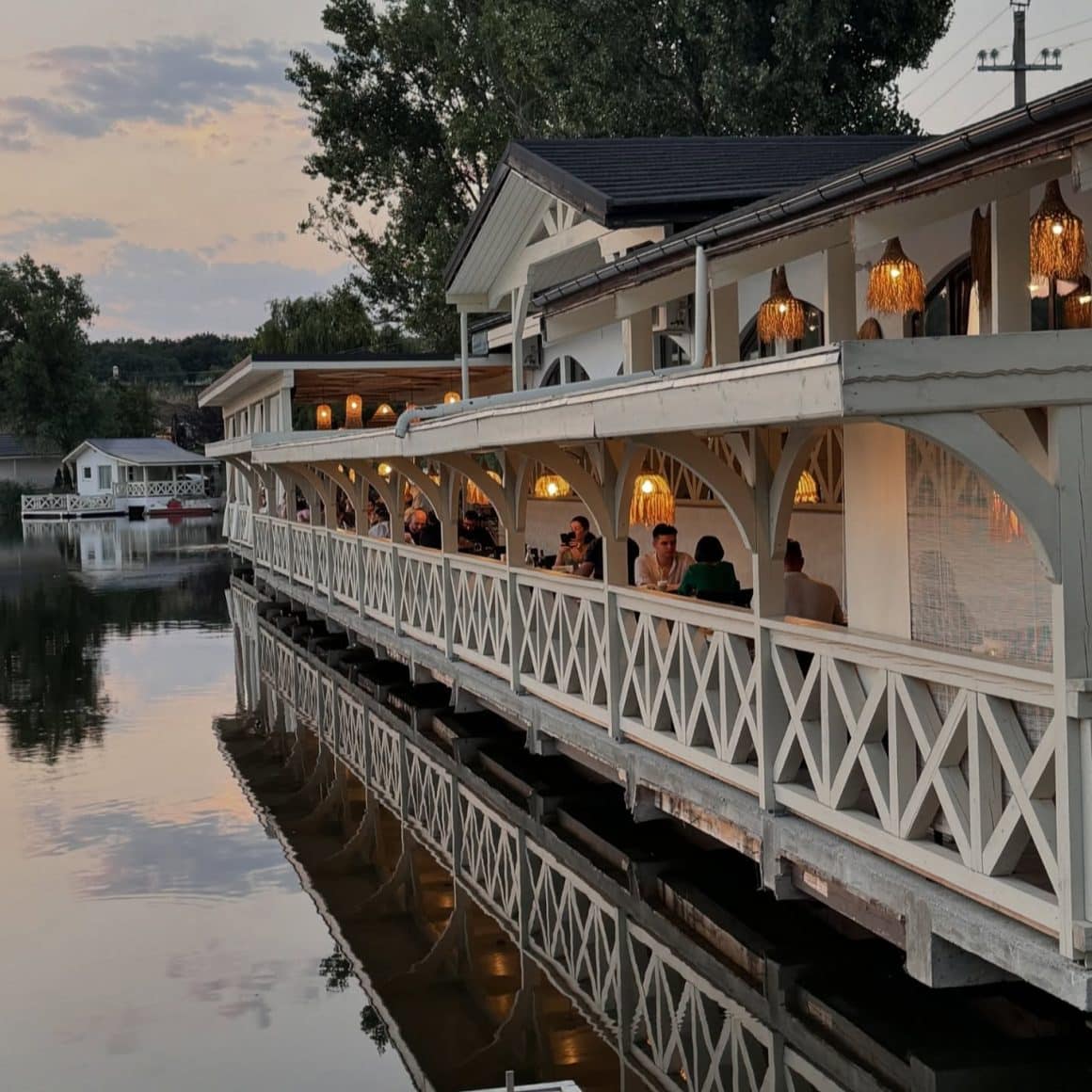 Oameni iau masa seara la rrestaurant Laguna Verde, pe malul lacului. restaurante lângă București