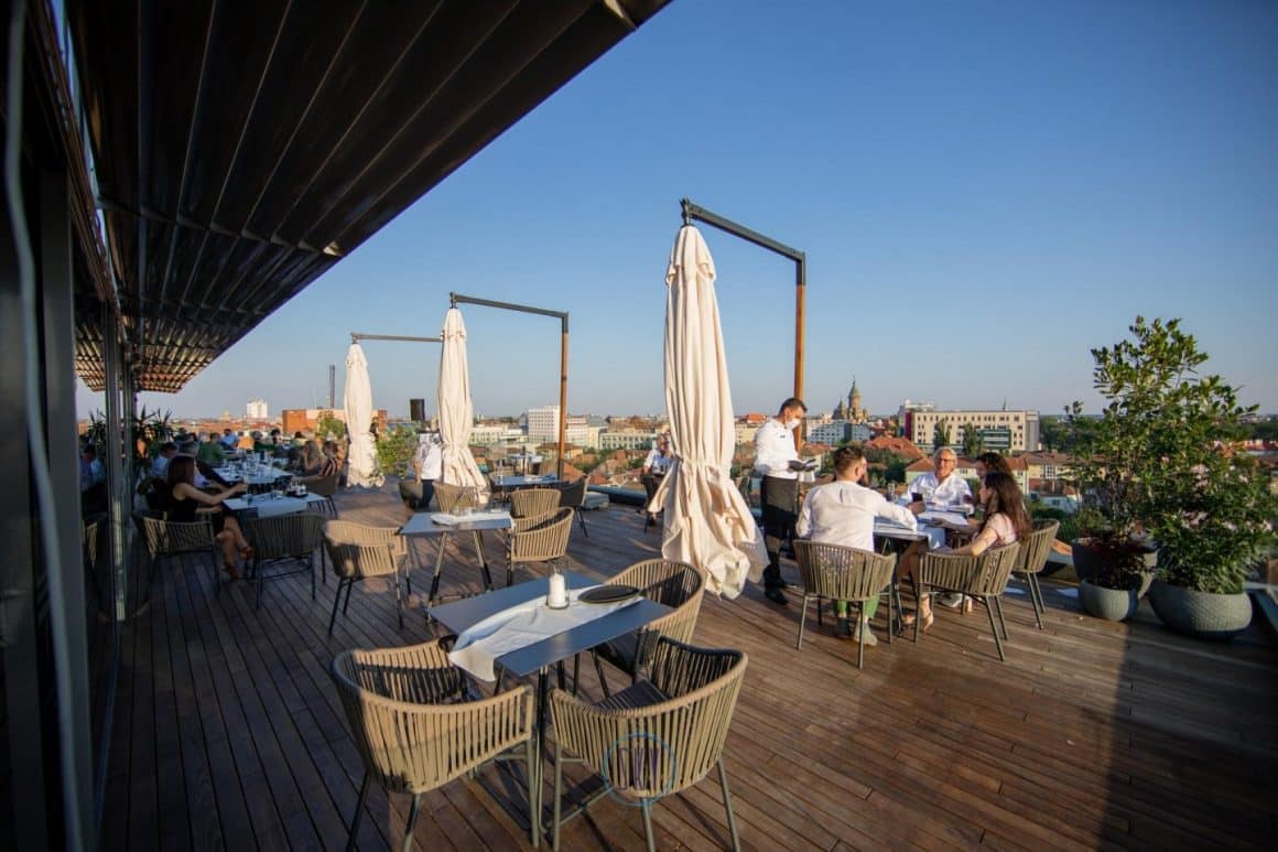 oameni iau masa pe o terasa rooftop. Sky restaurant Timișoara