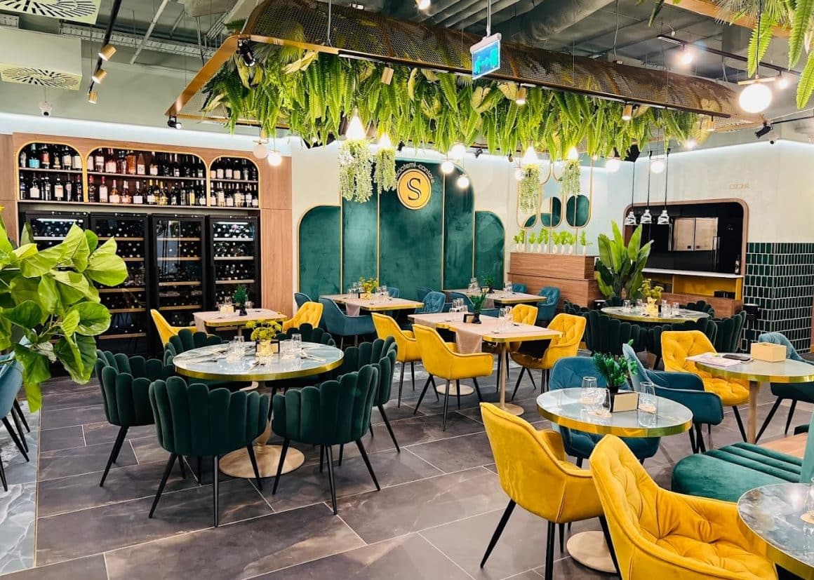 imagine din interiorul restaurantului Sciccheria Rosetti, decorat in nuante de verde si galben, cu mobilier elegant si scaune din catifea, si multe plante decorative. Locuri noi București