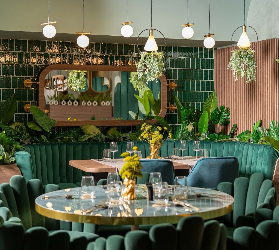 imagine din interiorul restaurantului Sciccheria Rosetti, decorat in nuante de verde si galben, cu mobilier elegant si scaune din catifea, si multe plante decorative. Locuri noi București
