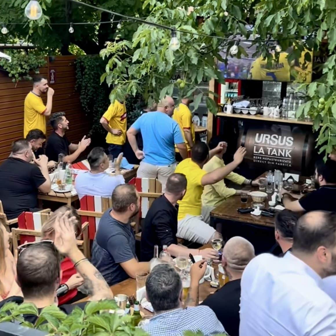 multi barbati asezati la mese in restaurant Draft Pub Tankeria Ursus din București, urmarind un meci difuzat la TV. terase și baruri sportive