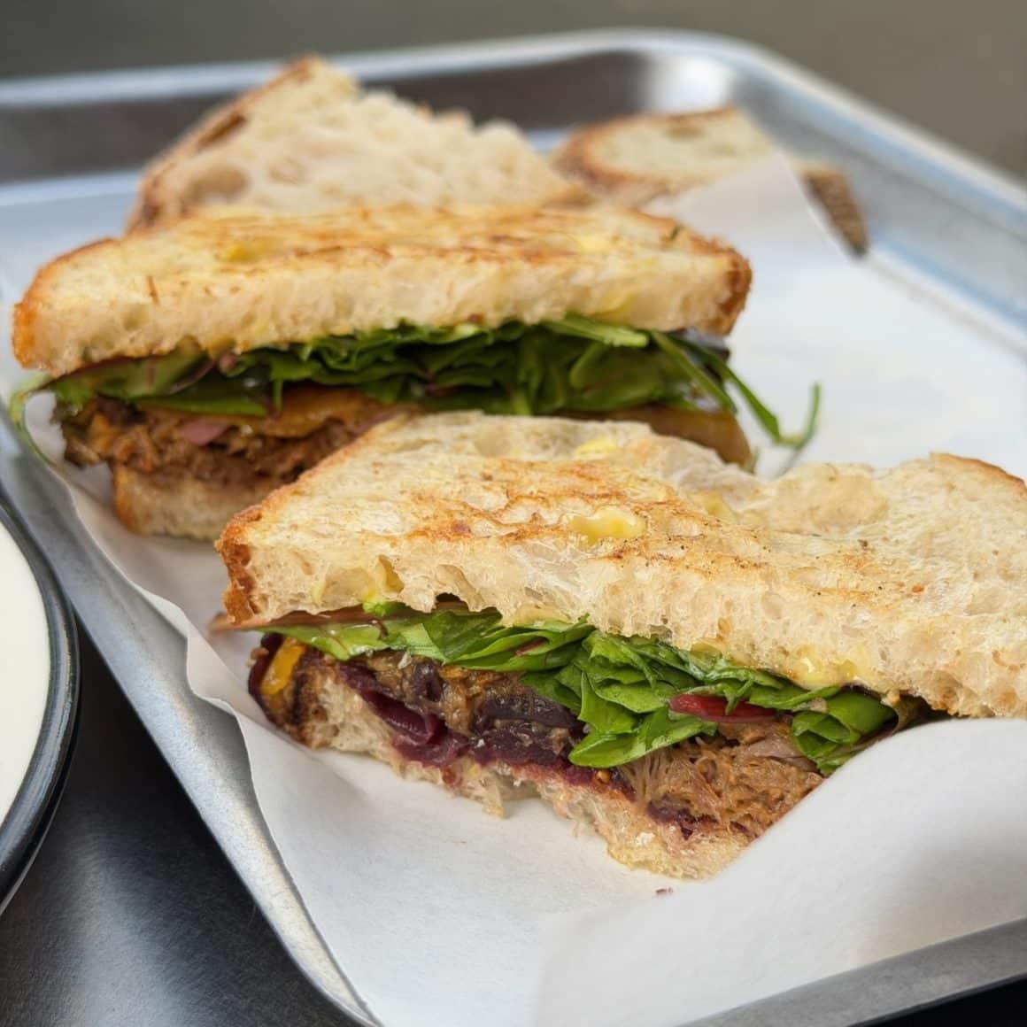 Sandwich de brunch cu pâine artizanală, carne fragedă și verdețuri proaspete, servit la Frudisiac Brod.