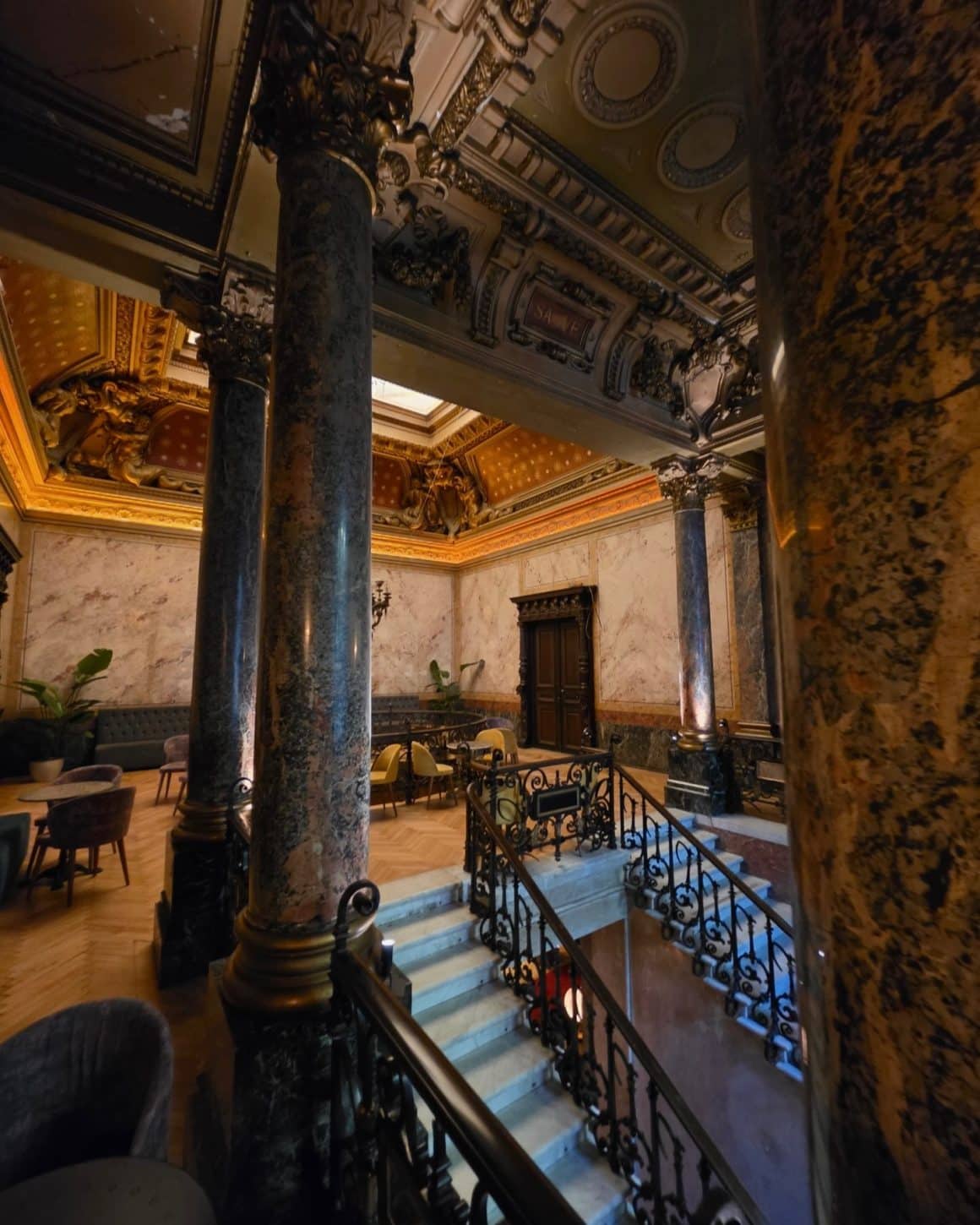 Interior cu scări monumentale, coloane din marmură și arhitectură de palat în Grand Café de Bucarest.