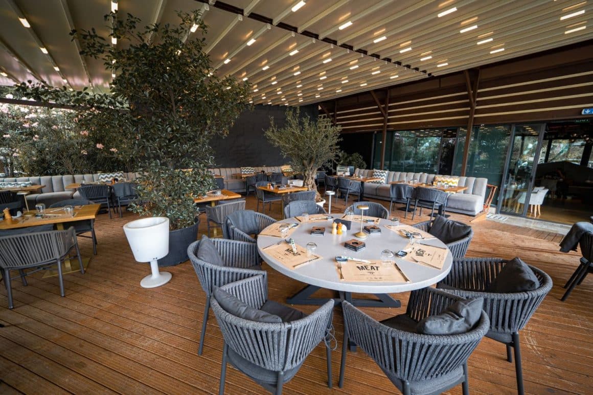 Terasă Argentine Herăstrău, spațioasă și modernă, cu mese rotunde și zone verzi, perfectă pentru seri de vară.