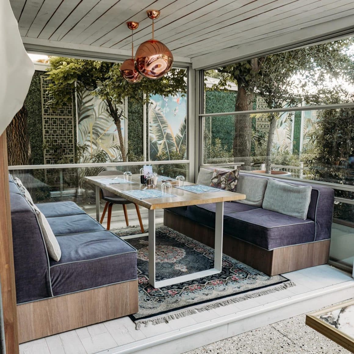 Colț intim la It Cucina Herăstrău, cu canapele confortabile, masă din lemn și lumină naturală, atmosferă relaxată de terasă.