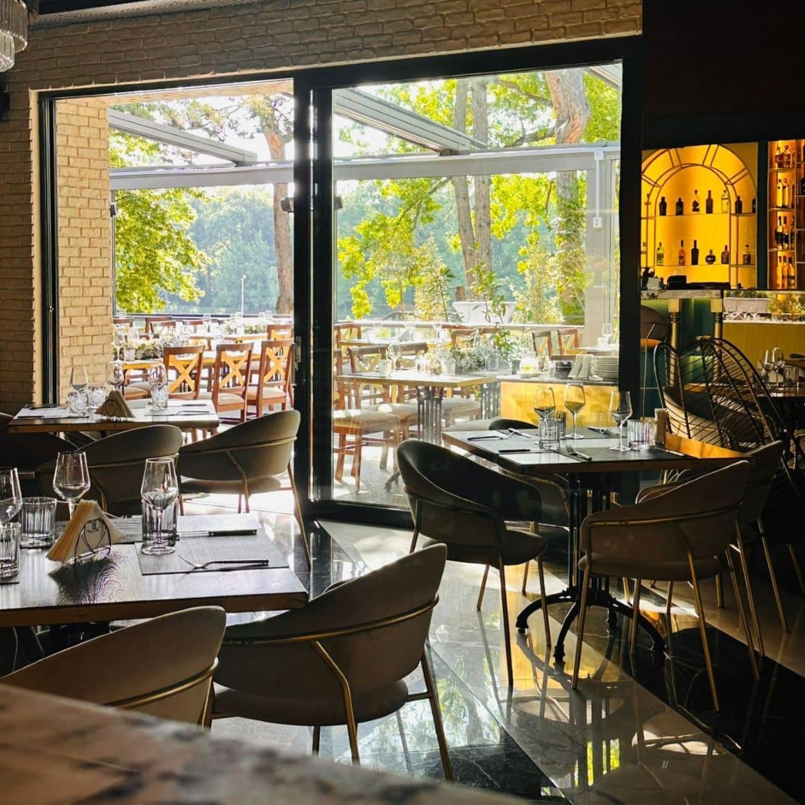 mese in restaurant Zeno, asezate in fata unui geam mare, cu vedere spre lac