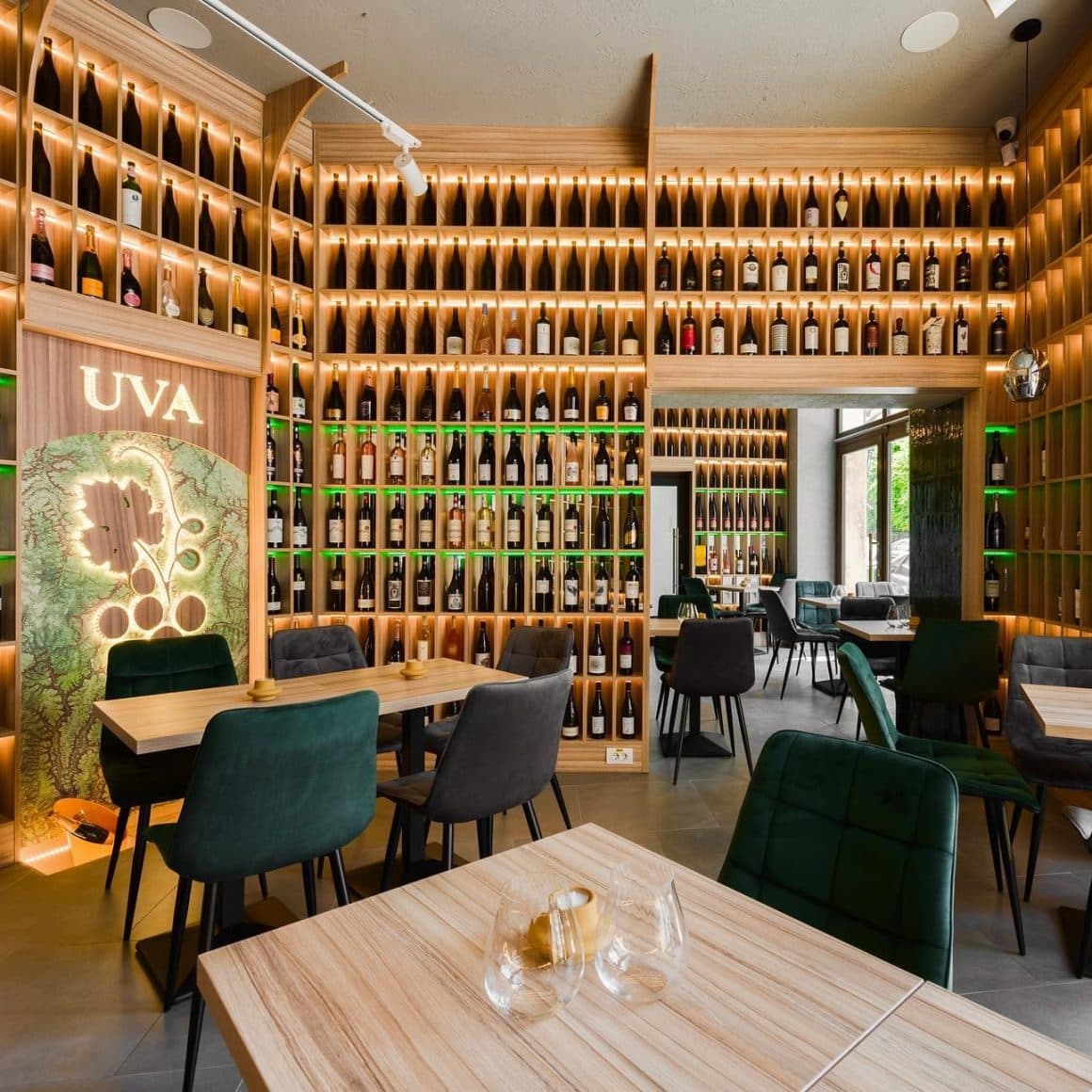 interiorul barului UVA Wine shop & Bar, cu mese din lemn si peretii acoperiti cu rafturi pline de sticle d evin. wine bars București