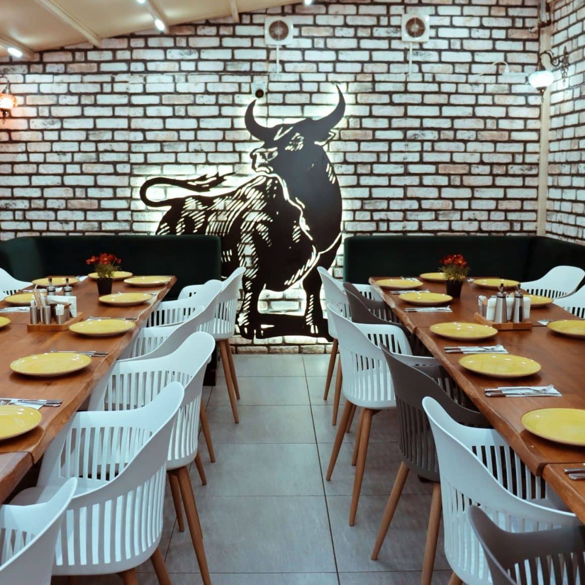 interiorul de la AYT Steakhouse, cu un perete cu tapet din caramida si un taur pictat.  Cele mai bune restaurante turcești din București