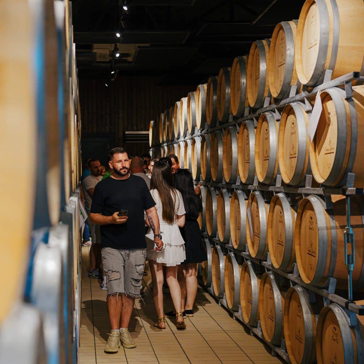 grup de turisti viziteaza beciurile de la crama Gîrboiu, pline cu butoaie de vin