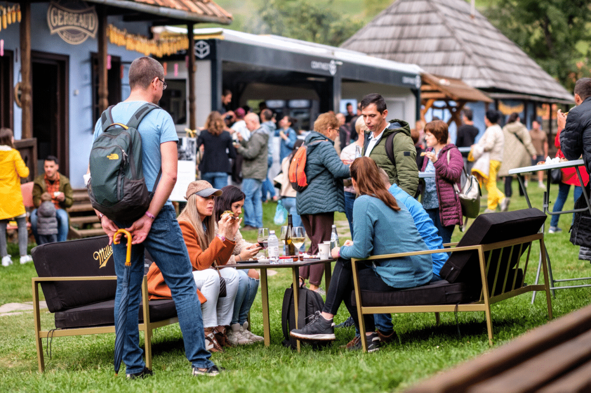 grup de prieteni mananca si discuta la o masa cu canapele asezata pe iarba la Taste of Transylvania. Târguri gastronomice de toamnă